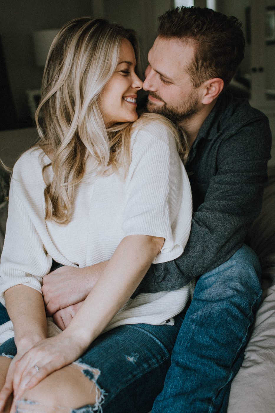 Engaged couple sitting on bed close together with their noses touching